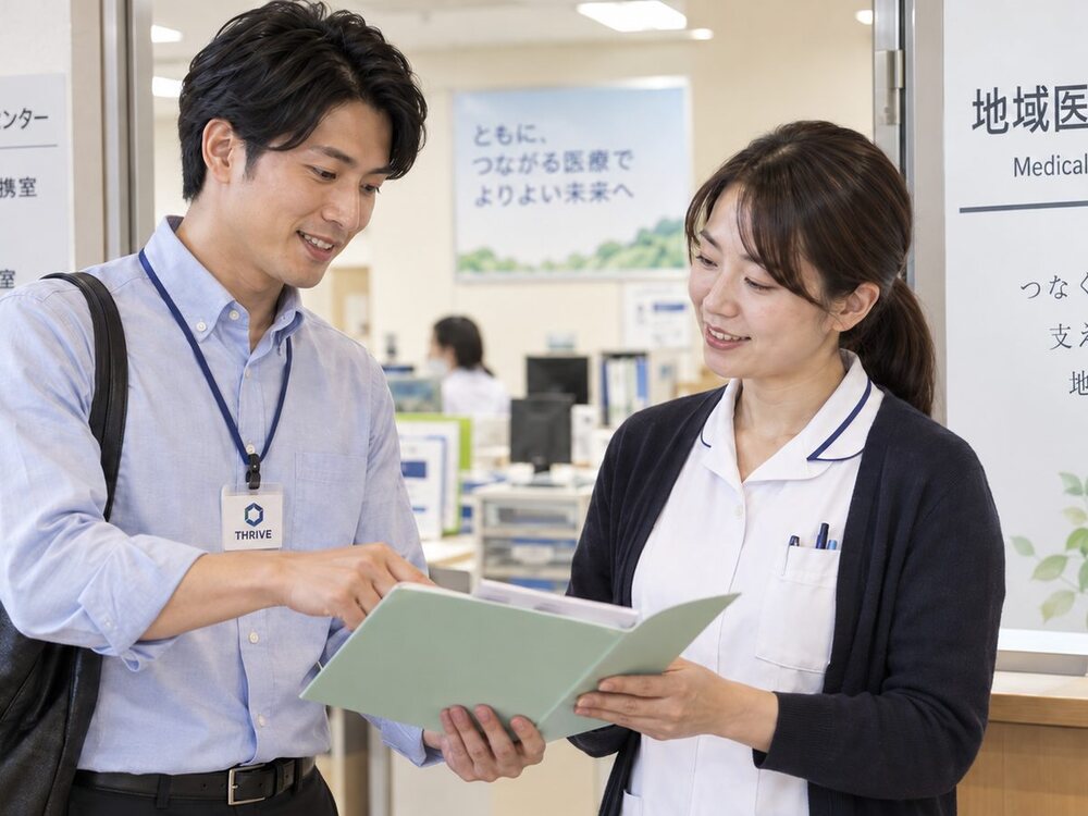 病院の地域医療連携室で、担当者と資料を見ながら話すTHRIVEスタッフ